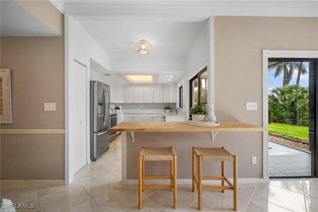 kitchen with a breakfast bar, white cabinets, stainless steel fridge with ice dispenser, decorative backsplash, and kitchen peninsula