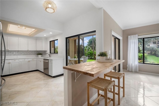 kitchen featuring white cabinetry, a breakfast bar area, wooden counters, decorative backsplash, and kitchen peninsula