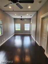 empty room featuring dark wood-type flooring and ceiling fan