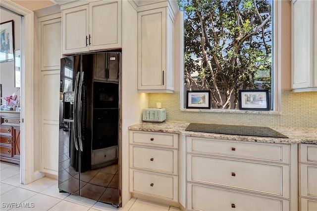 kitchen with light stone counters, black appliances, and cream cabinetry