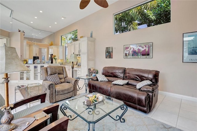 tiled living room with a wealth of natural light, ceiling fan, and a high ceiling