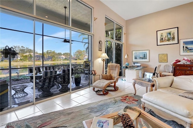 living room with ceiling fan, tile patterned floors, a high ceiling, and a water view