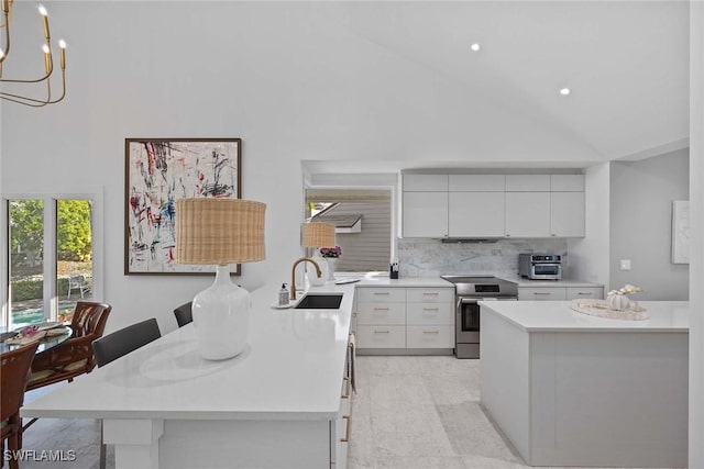 kitchen featuring sink, stainless steel electric range, white cabinetry, a kitchen breakfast bar, and decorative backsplash