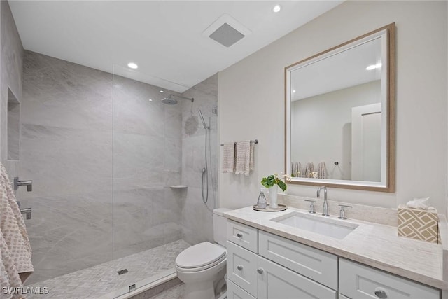 bathroom featuring vanity, toilet, and tiled shower