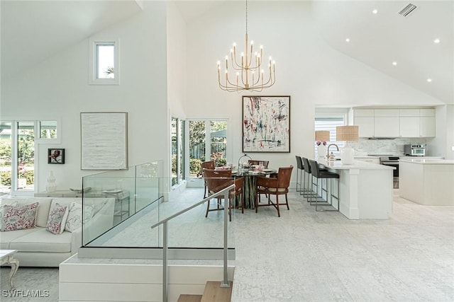 dining space with plenty of natural light, a notable chandelier, and high vaulted ceiling