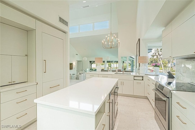 kitchen featuring stainless steel electric range, a center island, decorative light fixtures, kitchen peninsula, and a chandelier