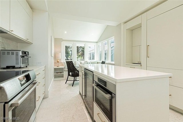 kitchen featuring lofted ceiling, stainless steel oven, a kitchen island, stove, and white cabinets