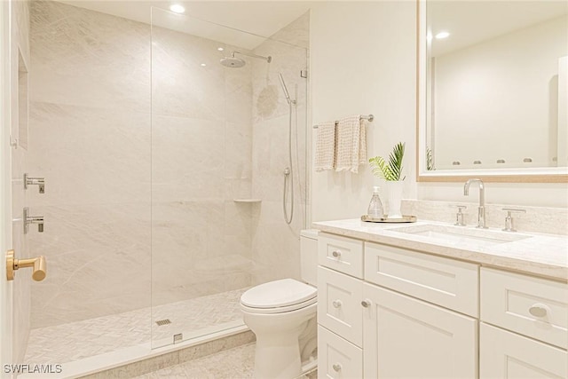 bathroom featuring tiled shower, vanity, and toilet