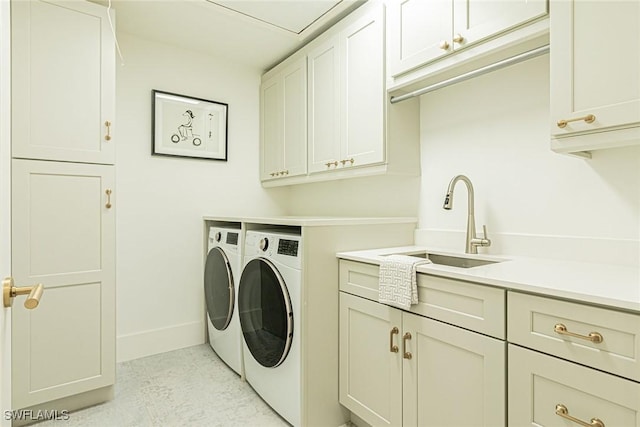 clothes washing area featuring cabinets, sink, and washer and dryer