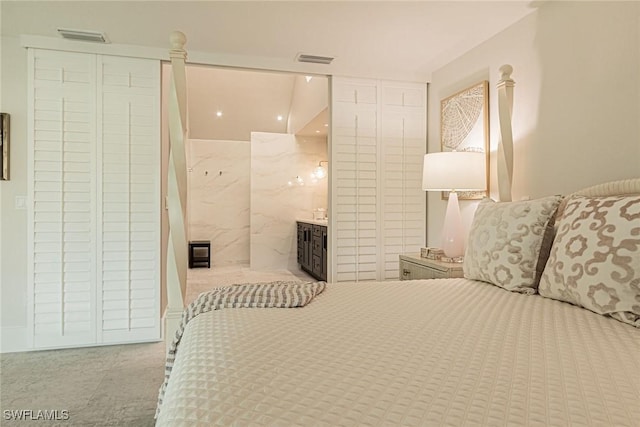 bedroom with connected bathroom and light colored carpet