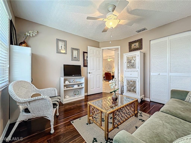 living room with ceiling fan, dark wood-type flooring, and a textured ceiling