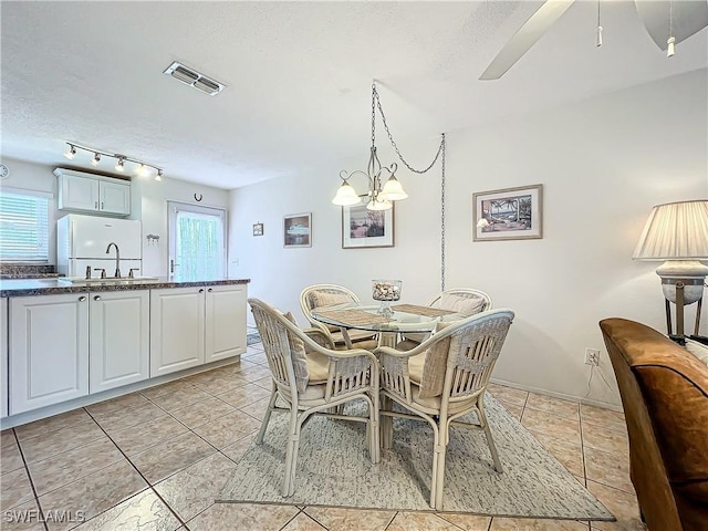 dining space featuring sink, a healthy amount of sunlight, light tile patterned floors, and a textured ceiling