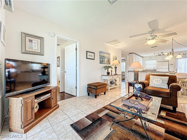 living room featuring light tile patterned floors, a textured ceiling, and ceiling fan