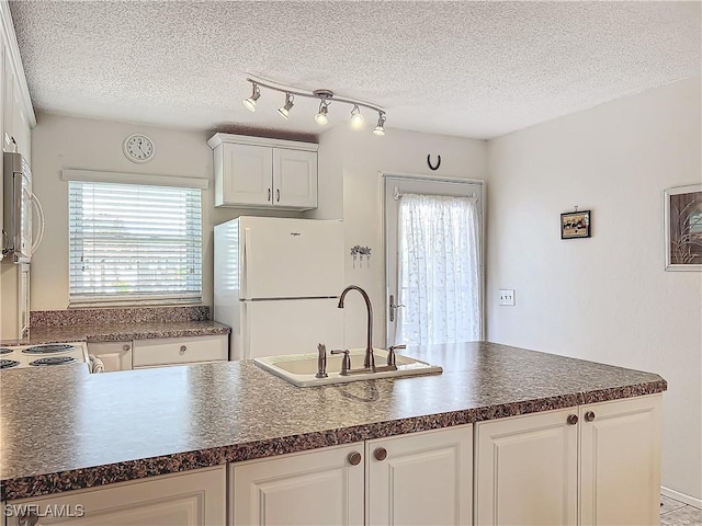 kitchen with white cabinetry, sink, white appliances, and a textured ceiling