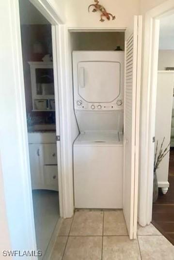 clothes washing area with stacked washing maching and dryer and light tile patterned floors