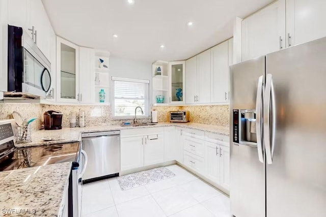 kitchen with stainless steel appliances, light stone countertops, sink, and white cabinets