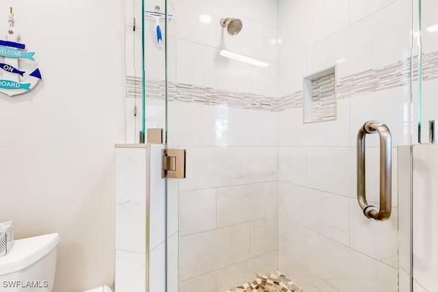 bathroom featuring toilet and a shower with door