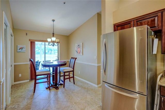 dining area featuring a notable chandelier, light tile patterned floors, and vaulted ceiling