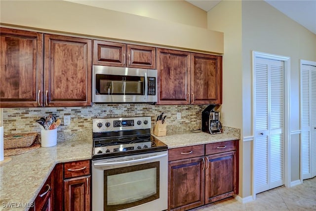 kitchen featuring decorative backsplash, light tile patterned flooring, light stone countertops, and appliances with stainless steel finishes