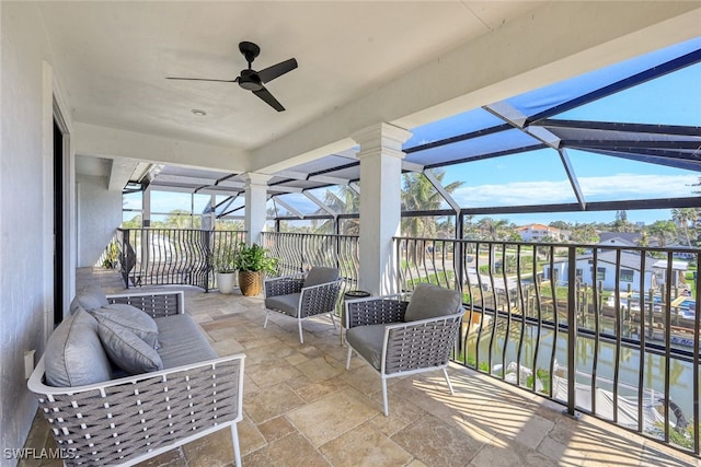 sunroom / solarium featuring ceiling fan and a water view