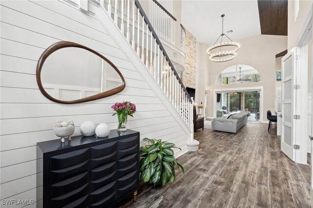 entrance foyer with a towering ceiling, wood-type flooring, and a notable chandelier