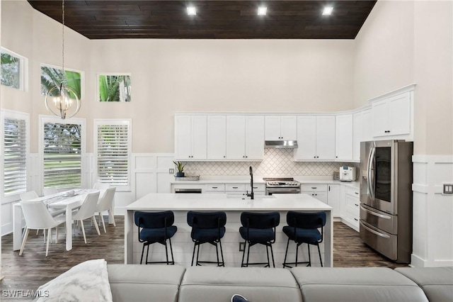 kitchen with a kitchen island with sink, stainless steel appliances, and white cabinets