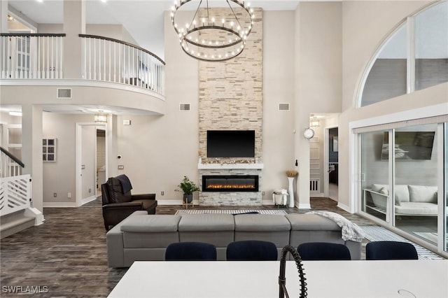 living room with a stone fireplace, wood-type flooring, and a chandelier