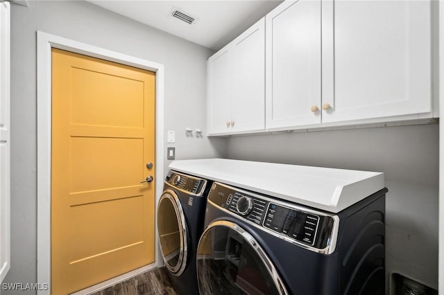 laundry area featuring cabinets, dark hardwood / wood-style floors, and washing machine and dryer