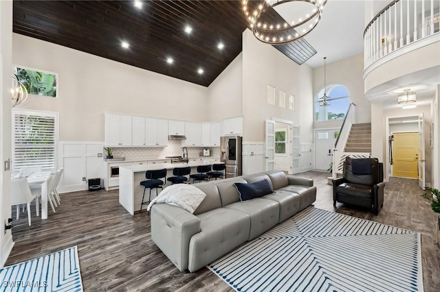 living room with dark hardwood / wood-style flooring, sink, and high vaulted ceiling