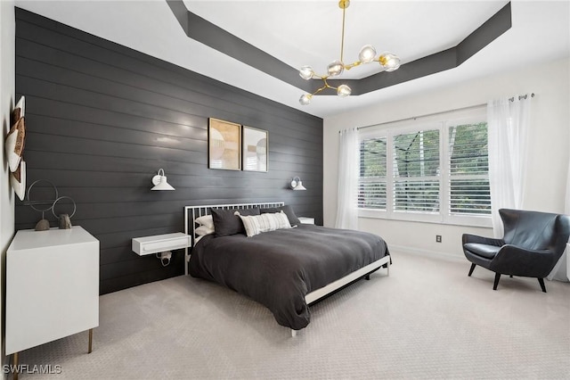 bedroom with a raised ceiling, light colored carpet, and a chandelier