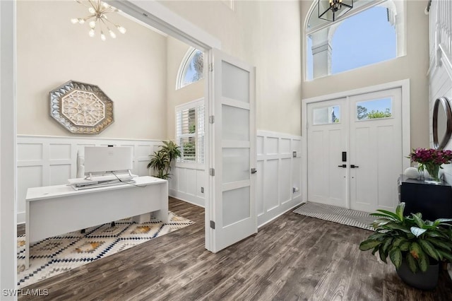 entrance foyer with an inviting chandelier, a towering ceiling, and dark hardwood / wood-style flooring