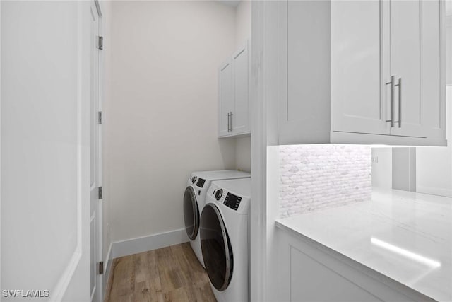 washroom featuring cabinets, washing machine and dryer, and light hardwood / wood-style floors