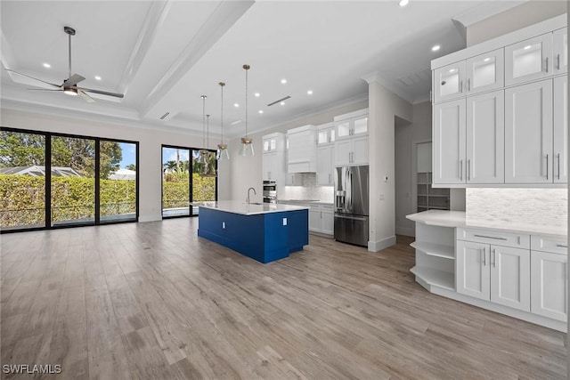 kitchen featuring pendant lighting, appliances with stainless steel finishes, a center island with sink, and white cabinets