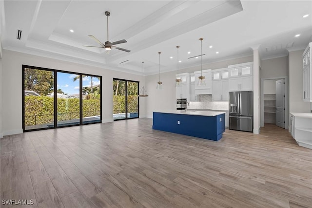 kitchen featuring a center island, a tray ceiling, stainless steel fridge, pendant lighting, and white cabinets