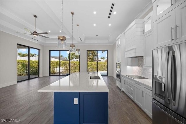 kitchen featuring sink, white cabinetry, decorative light fixtures, appliances with stainless steel finishes, and an island with sink