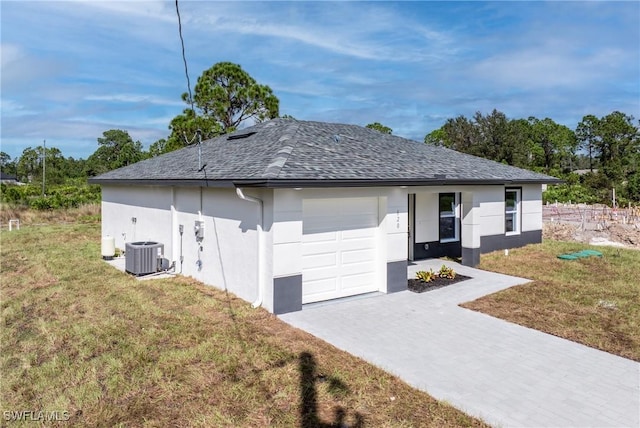 view of front of house with cooling unit, a garage, and a front lawn