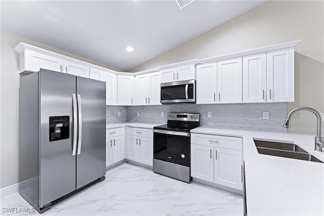 kitchen featuring sink, appliances with stainless steel finishes, tasteful backsplash, white cabinets, and vaulted ceiling