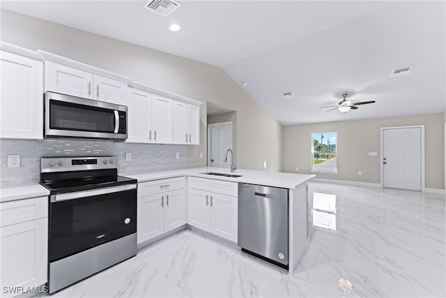 kitchen featuring lofted ceiling, sink, white cabinets, kitchen peninsula, and stainless steel appliances