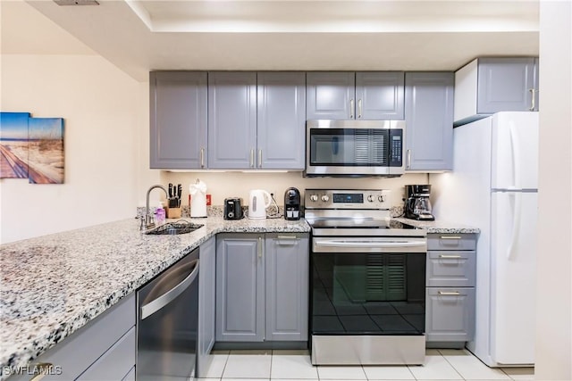 kitchen featuring light stone counters, sink, gray cabinets, and appliances with stainless steel finishes