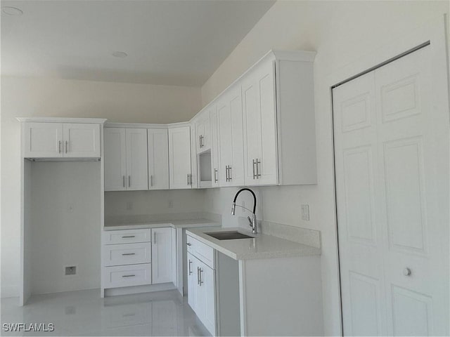 kitchen featuring white cabinets, light countertops, and a sink