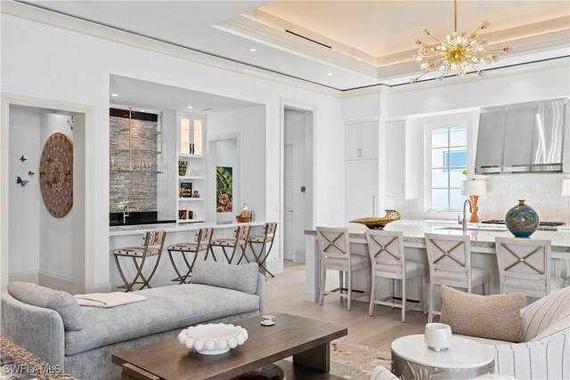 565 Anchor Rode Dr, Naples, FL 34103 - living area featuring a notable chandelier, light wood-type flooring, crown molding, and a raised ceiling