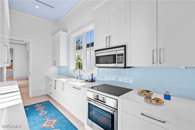 565 Anchor Rode Dr, Naples, FL 34103 - kitchen featuring ornamental molding, white cabinets, appliances with stainless steel finishes, light countertops, and backsplash