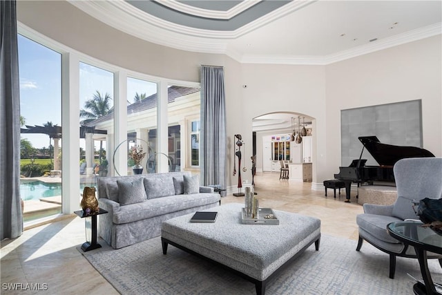 living area featuring crown molding, baseboards, arched walkways, and a towering ceiling