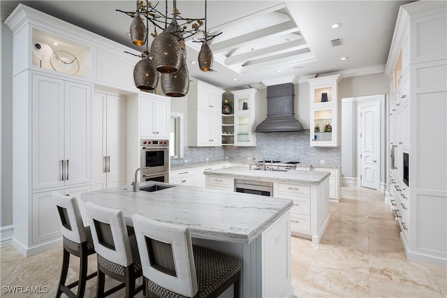 kitchen with white cabinetry, an island with sink, custom range hood, and sink