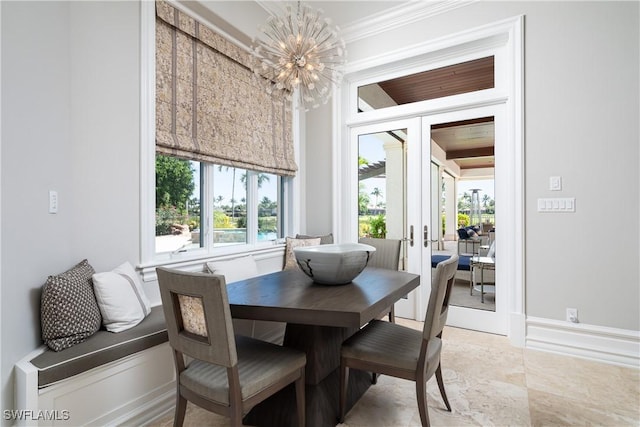 dining area featuring a notable chandelier, crown molding, and french doors