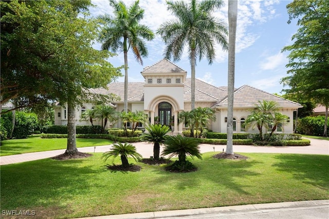 mediterranean / spanish home with a tiled roof, french doors, a front lawn, and stucco siding