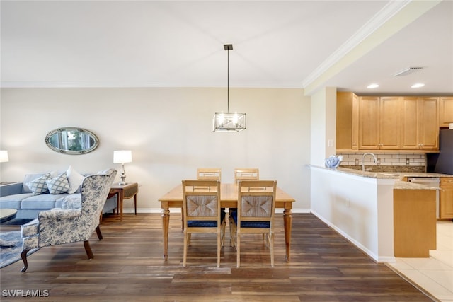 dining area with dark hardwood / wood-style flooring, a notable chandelier, ornamental molding, and sink