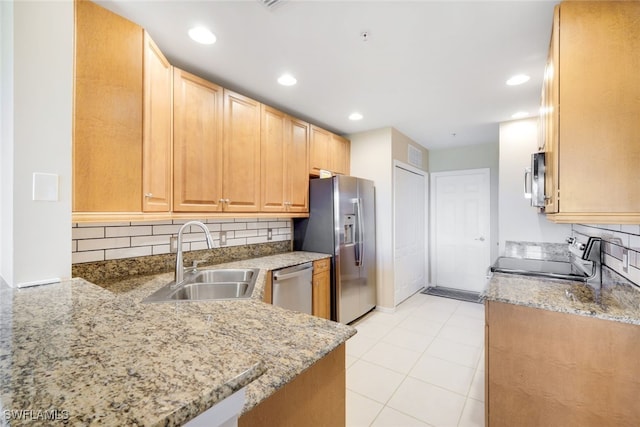 kitchen with appliances with stainless steel finishes, sink, decorative backsplash, light stone counters, and kitchen peninsula