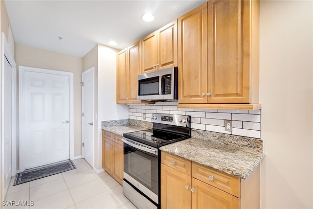 kitchen with light stone counters, decorative backsplash, stainless steel appliances, and light tile patterned flooring