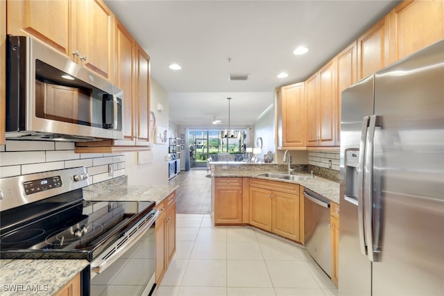 kitchen featuring sink, appliances with stainless steel finishes, hanging light fixtures, light stone counters, and kitchen peninsula